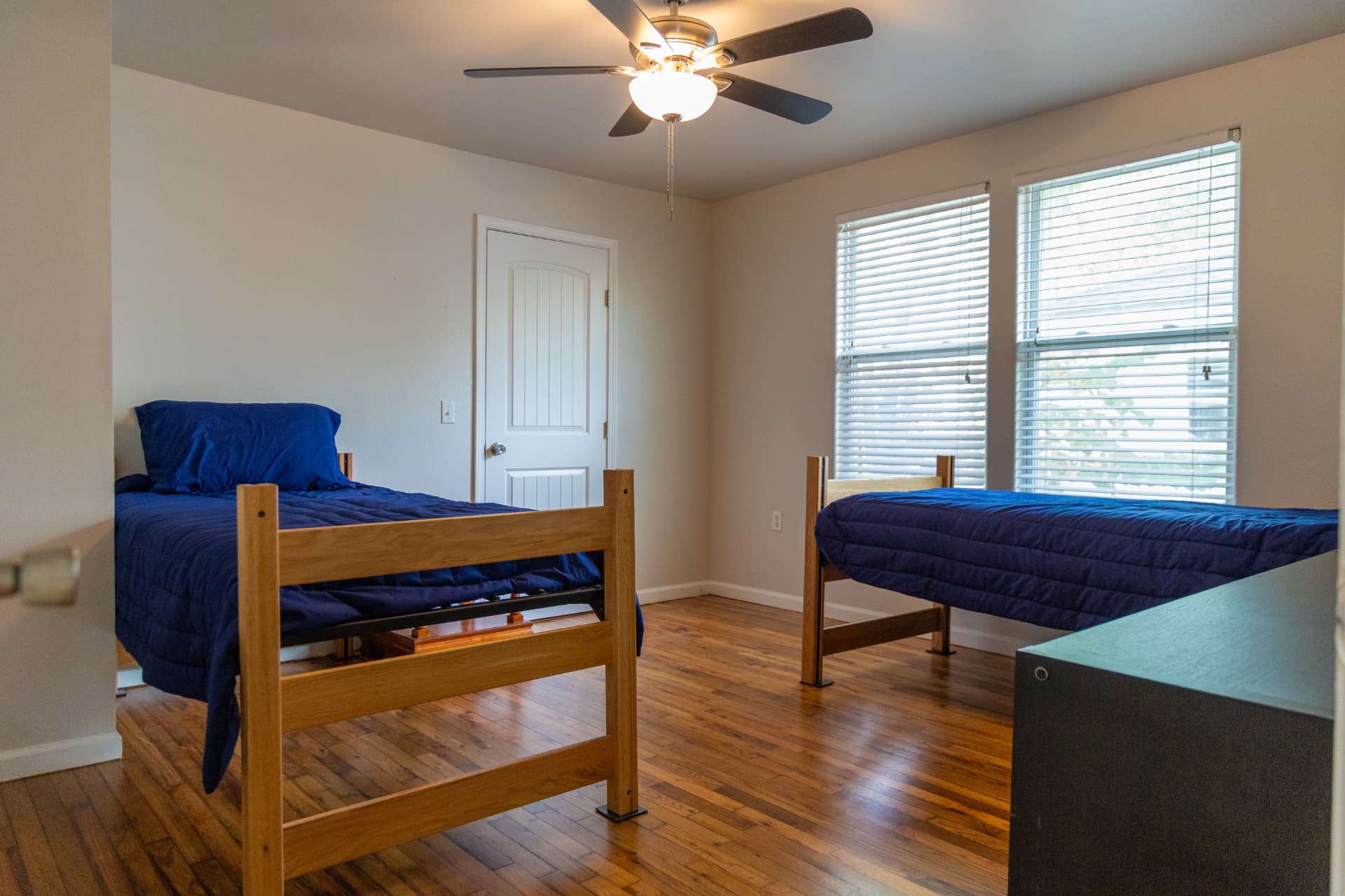 Bedroom with two twin beds, ceiling fan, and large windows
