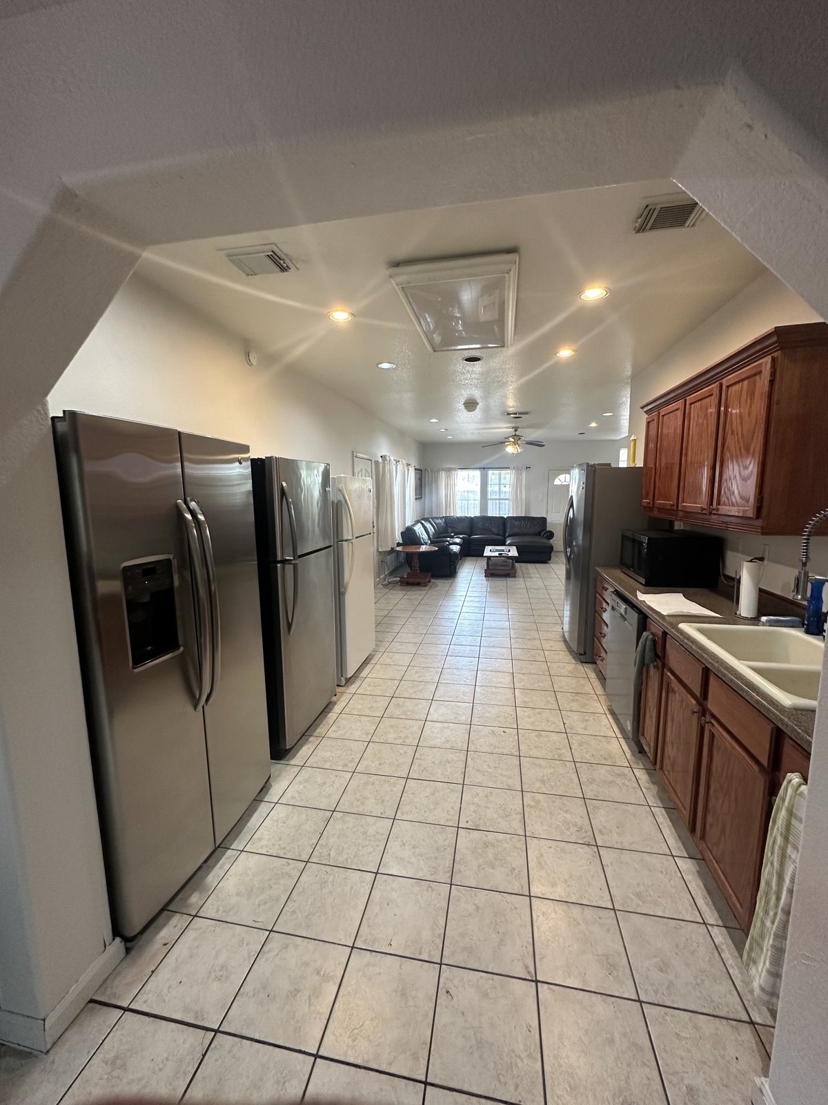 Large kitchen with four refrigerators opening onto the living room
