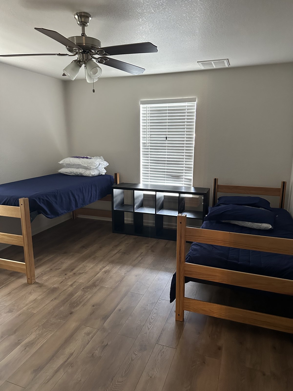 Spacious bedroom with two twin beds and wood-look flooring